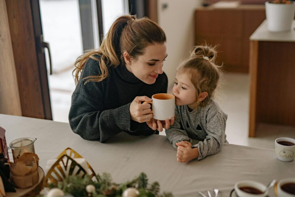 A warm scene of a mother and daughter sharing a cozy beverage at home.